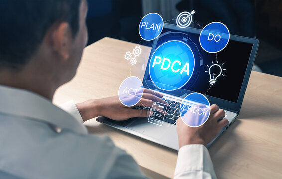 Business professional working on laptop with PDCA cycle concepts visually represented around, focusing on planning, doing, checking, and acting for continuous improvement. Bitwise.