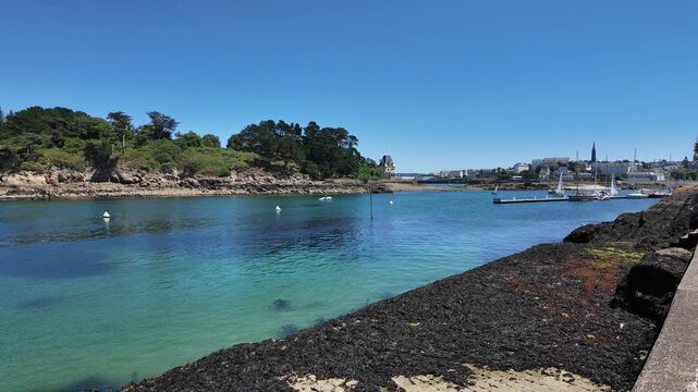 DOUARNENEZ, FRANCE &ndash; July 4, 2026: Slow right-to-left pan across a turquoise bay with anchored sailboats and a rocky island in Douarnenez, Brittany, France. Calm summer day on the Atlantic coast with 