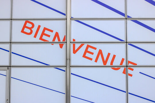Bienvenue welcome sign on glass facade at modern airport terminal