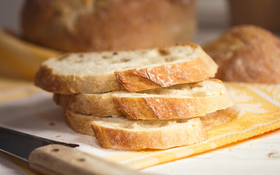Slices of homemade white wheat bread with crispy crust on a rustic kitchen table.