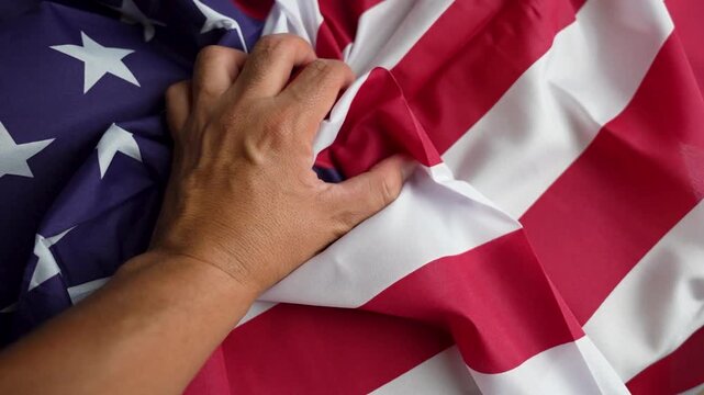Slow motion of a man's hand wrinkling the United States flag