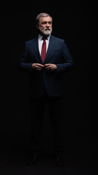 Studio portrait of senior businessman in suit on dark background