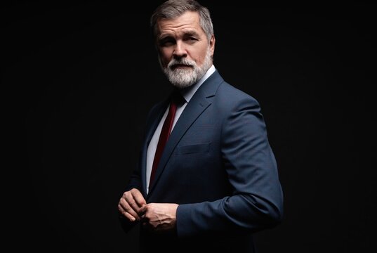 Studio portrait of senior businessman in suit on dark background