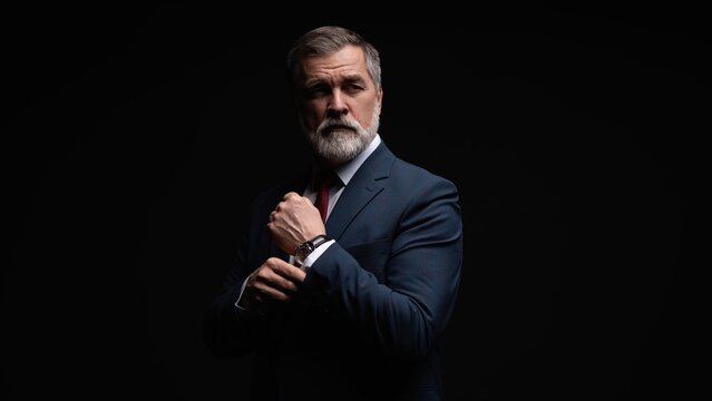 Studio portrait of senior businessman in suit on dark background