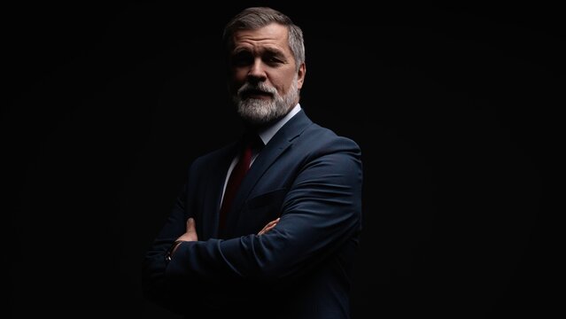 Studio portrait of senior businessman in suit on dark background