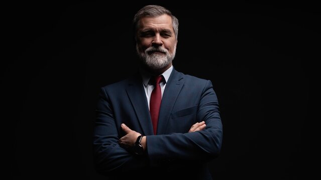 Studio portrait of senior businessman in suit on dark background