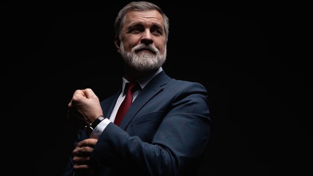 Studio portrait of senior businessman in suit on dark background