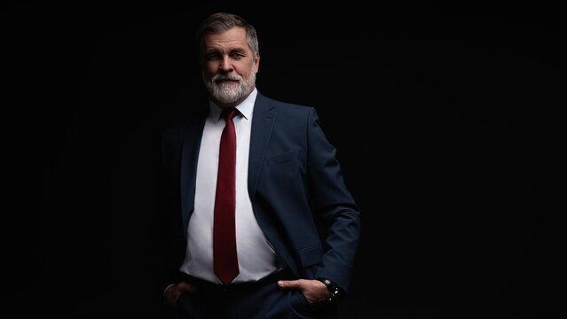 Studio portrait of senior businessman in suit on dark background