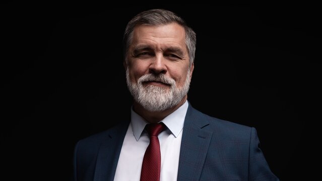 Studio portrait of senior businessman in suit on dark background