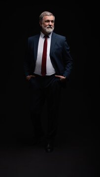 Studio portrait of senior businessman in suit on dark background