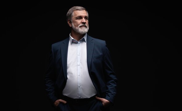 Studio portrait of senior businessman in suit on dark background