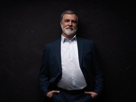 Studio portrait of senior businessman in suit on dark background