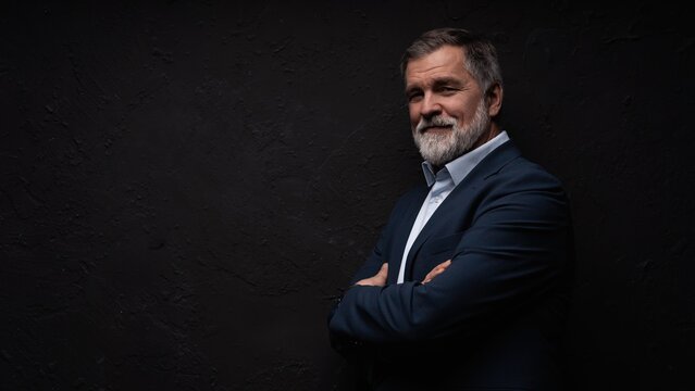 Studio portrait of senior businessman in suit on dark background