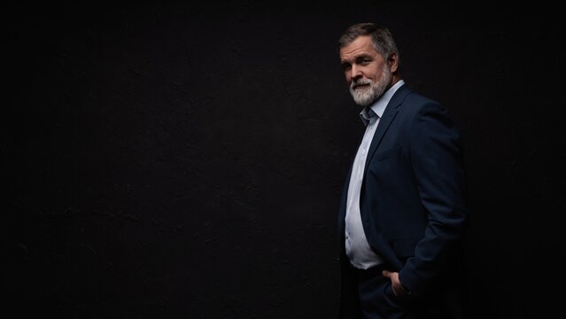 Studio portrait of senior businessman in suit on dark background