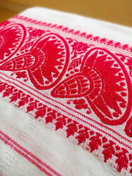 Close-up of a traditional Assamese Gamosa fabric texture featuring iconic red and white woven patterns.