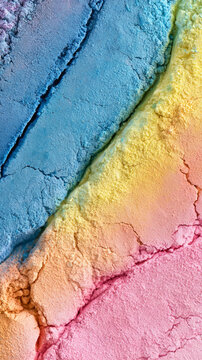 Colorful cosmetic powder creates a diagonal spectrum of vibrant hues, presenting a textured surface with dry, pigment-rich ingredients and natural cracks