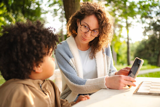 Mother and son using cell phone playing game in park