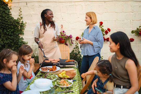 Diverse friends and children enjoying barbecue dinner party outdoors