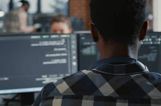Programmer Coding on Laptop with Multiple Screens in a software development office, showing programmers collaborating on source code, algorithms and data coding workflow.