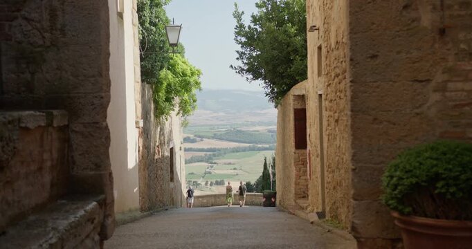 Tourists admiring tuscany landscape from pienza alley