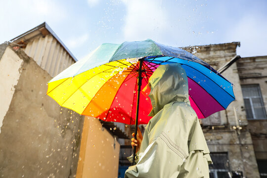 Woman with rainbow umbrella in rain outside