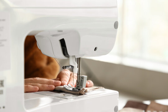 Female hands using sewing machine in atelier, closeup