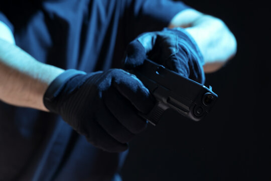 Man with gun reloading on black background, closeup