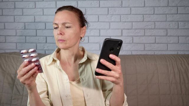 Woman with poor eyesight reading pill instructions on smartphone. Concerned woman with vision problems struggling to read medical instructions on a blister pack of pills, using her smartphone