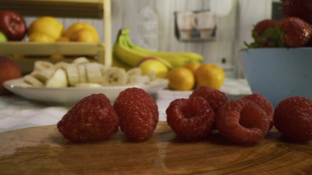 Raspberries on cutting board with other fruit around kitchen - tracking shot