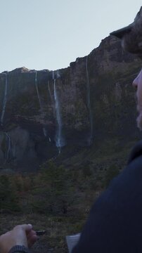 Close up of a hiker eating, with the Casta&ntilde;o Overa glacier and cascading waterfalls in the blurred background, located in Nahuel Huapi National Park, Argentina.