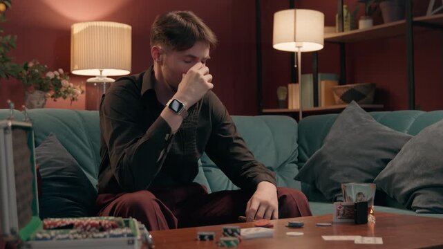 Angry upset Caucasian man gambler throwing poker cards holding cigar losing bet at home casino mad frustrated male player playing lose failure game night gambling addiction guy sitting at sofa indoors