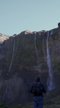 Hiker with a backpack standing before the massive Casta&ntilde;o Overa waterfall, viewing the cascading water on the rocky cliff face in Nahuel Huapi National Park, Argentina.