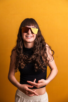 Woman dancing wearing trendy sunglasses on yellow background