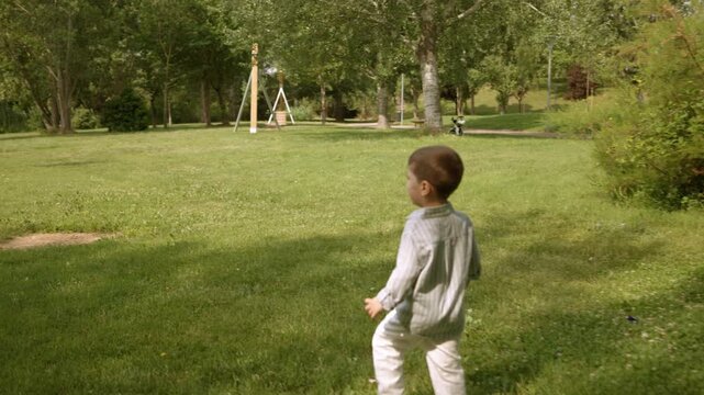 Little boy running away in a green park on a sunny day