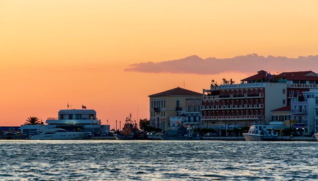 Vathy, Greece - July 25, 2026: Sunset view of houses on the waterfront in Vathy on Samos Island, Greece, showing coastal buildings, warm evening light, harbor scenery, and calm Aegean Sea water