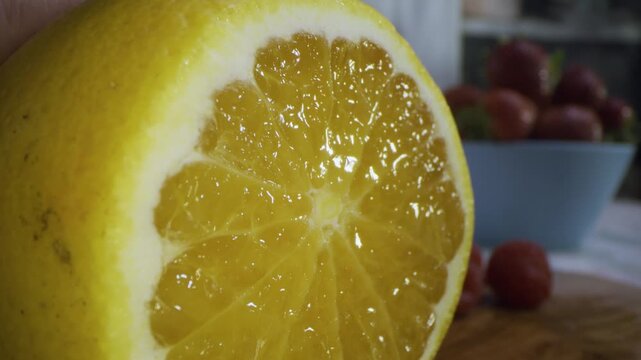 Large knife slicing through juicy orange in kitchen - extra closeup shot