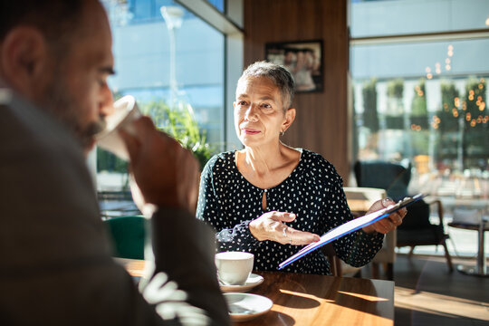 Senior businesswoman meeting with colleague in cafe