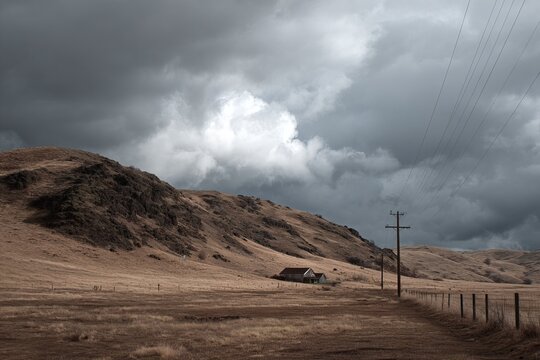 Dramatic landscape - Stormy skies over rural hills and a lone structure.