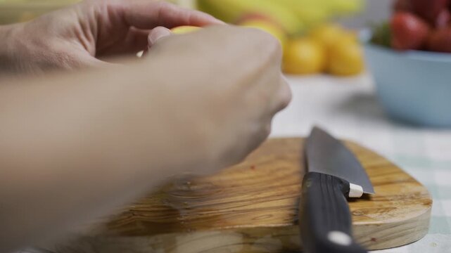 Hands of woman cutting open peach and slicing it up on cutting board