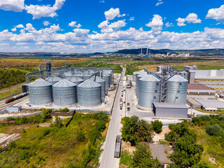 A wide view of grain silos and a road with trucks in a rural area during a sunny day © DSMT