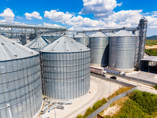 Large grain storage facility with silos and trucks under blue sky in daytime © DSMT