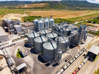 Industrial facility with grain silos and rail tracks in a rural area during daytime hours © DSMT