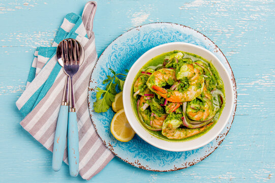 MEXICAN CUISINE. Aguachile de camaron. Prawns aguachile. Shrimps eviche cebiche with cucumber, lemon and purple onion. Top view, blue background