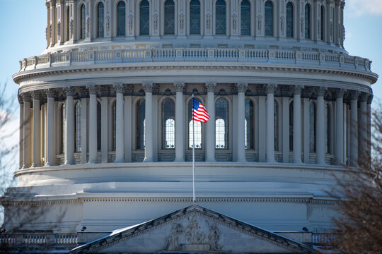 Capitol with American flag near landmark in Washington DC. American flag near Capitol with classical architecture. US flag on Capitol as national symbol. Capitol with American flag for background.