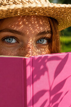 Woman reading outdoors under sunlight.