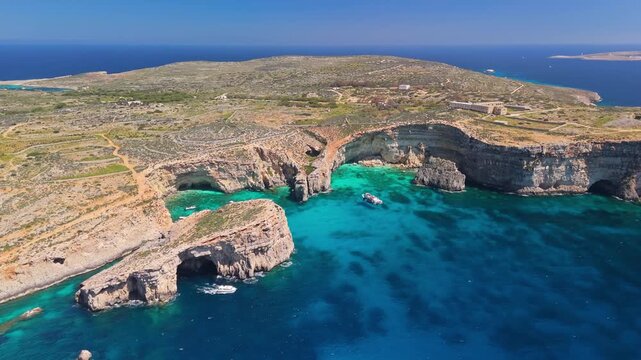 Blue Lagoon, Comino, Malta, with turquoise crystal clear water, rocky cliffs, caves and boats in the Mediterranean Sea, scenic coastal landscape captured in aerial view.