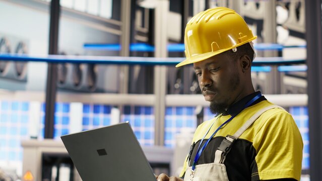 A smart factory engineer performs maintenance with laptop software and analyzes IoT sensor data while managing the operational reliability of photovoltaic systems.