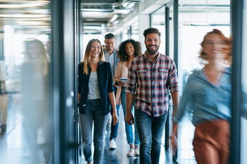 Obraz premium Coworkers laughing while walking a sunlit office hallway