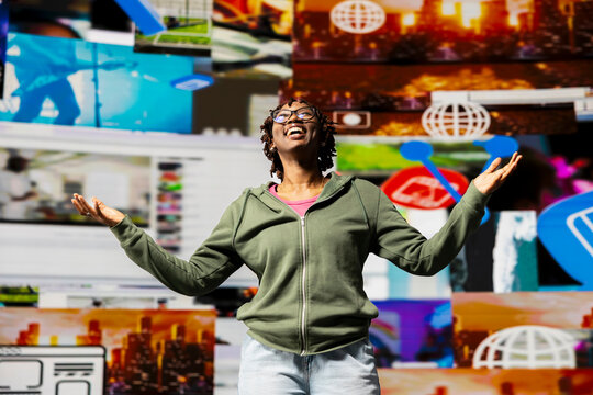 Happy woman spreading arms, looking upwards to video wall, enjoying digital age lifestyle, expressing happiness; Cheerful viewer enjoying technology bridging people worldwide.