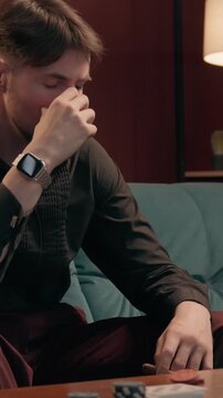 Angry upset Caucasian man gambler throwing poker cards holding cigar losing bet at home casino mad frustrated male player playing lose failure game night gambling addiction guy sitting at sofa indoors